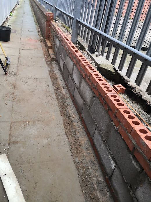 Commercial brick wall under construction with concrete blocks and facing bricks during a professional bricklaying project in Hertfordshire.