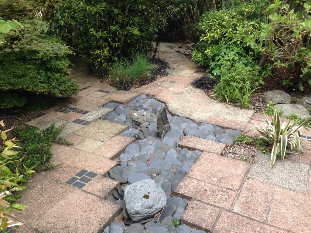 Decorative garden pathway with natural stone and rock feature landscaped by RidgeOak in Hertfordshire.