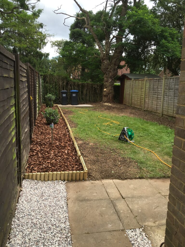 Completed garden landscaping with decorative bark borders, white gravel edging and refreshed lawn.
