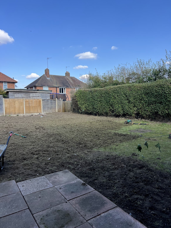 Garden landscaping project under construction after clearance and ground preparation before new lawn installation.