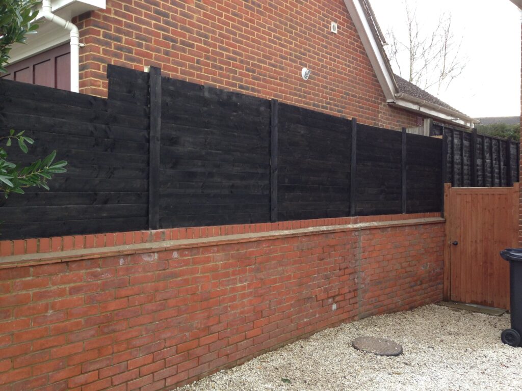 New black privacy fence with timber gate professionally installed at a residential property in Hertfordshire.