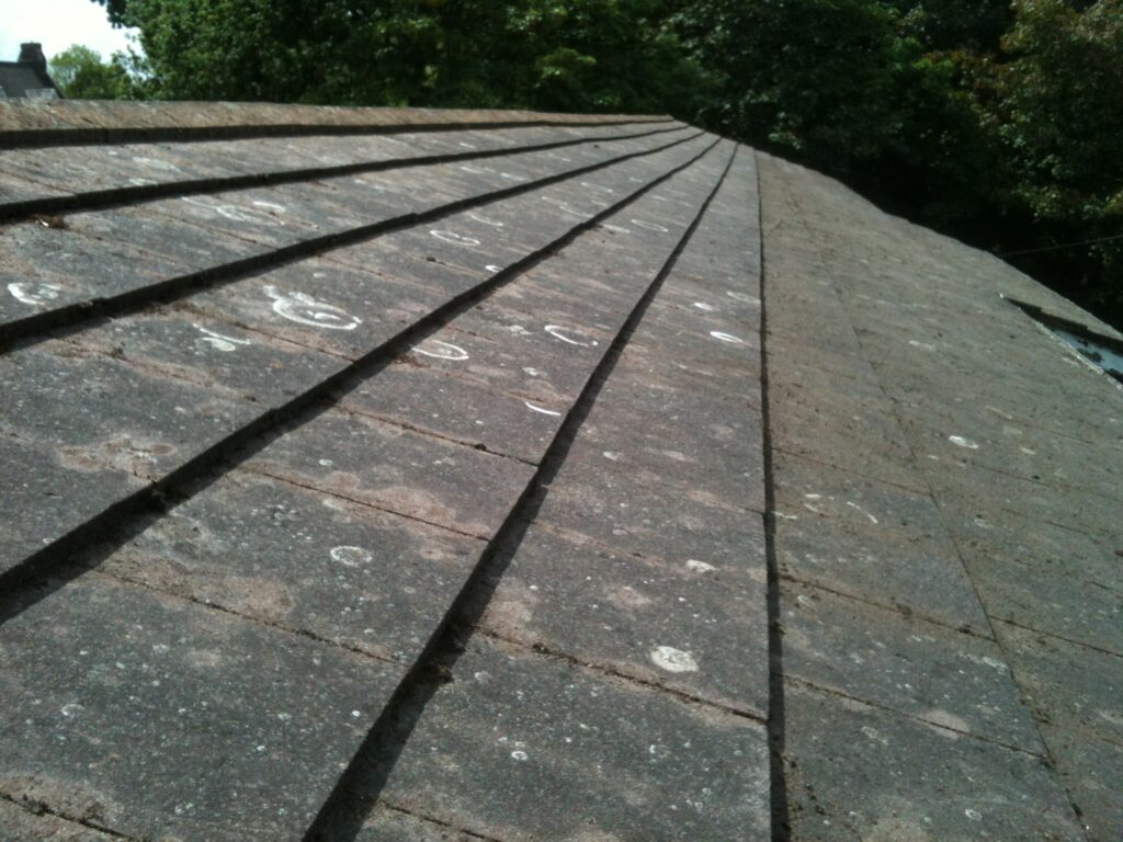 Weathered concrete tiled roof with lichen and organic staining before professional roof cleaning in Hertfordshire.