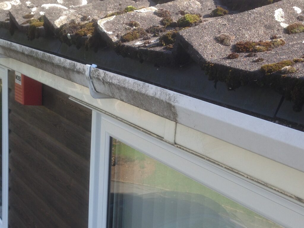 Before roof cleaning showing moss-covered roof tiles and dirty gutters on a property in Hertfordshire.