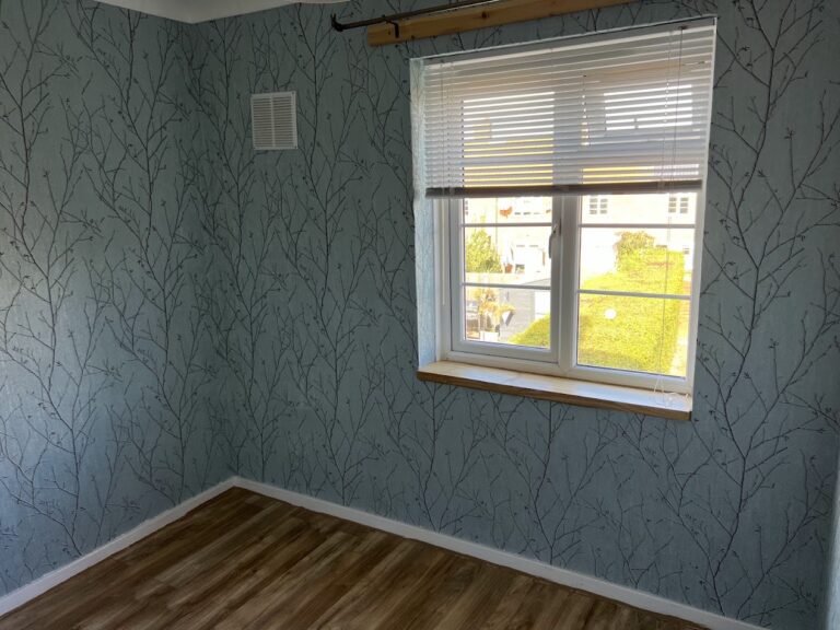 Handmade pine wooden window sill installed during room renovation, with tree-patterned wallpaper and white window blinds in Welwyn Garden City.
